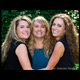 Three sisters with long curly hair photographed in a group hug in the garden