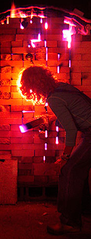 woman with curly hair in the glow of her firey pottery kiln in kennebunkport maine